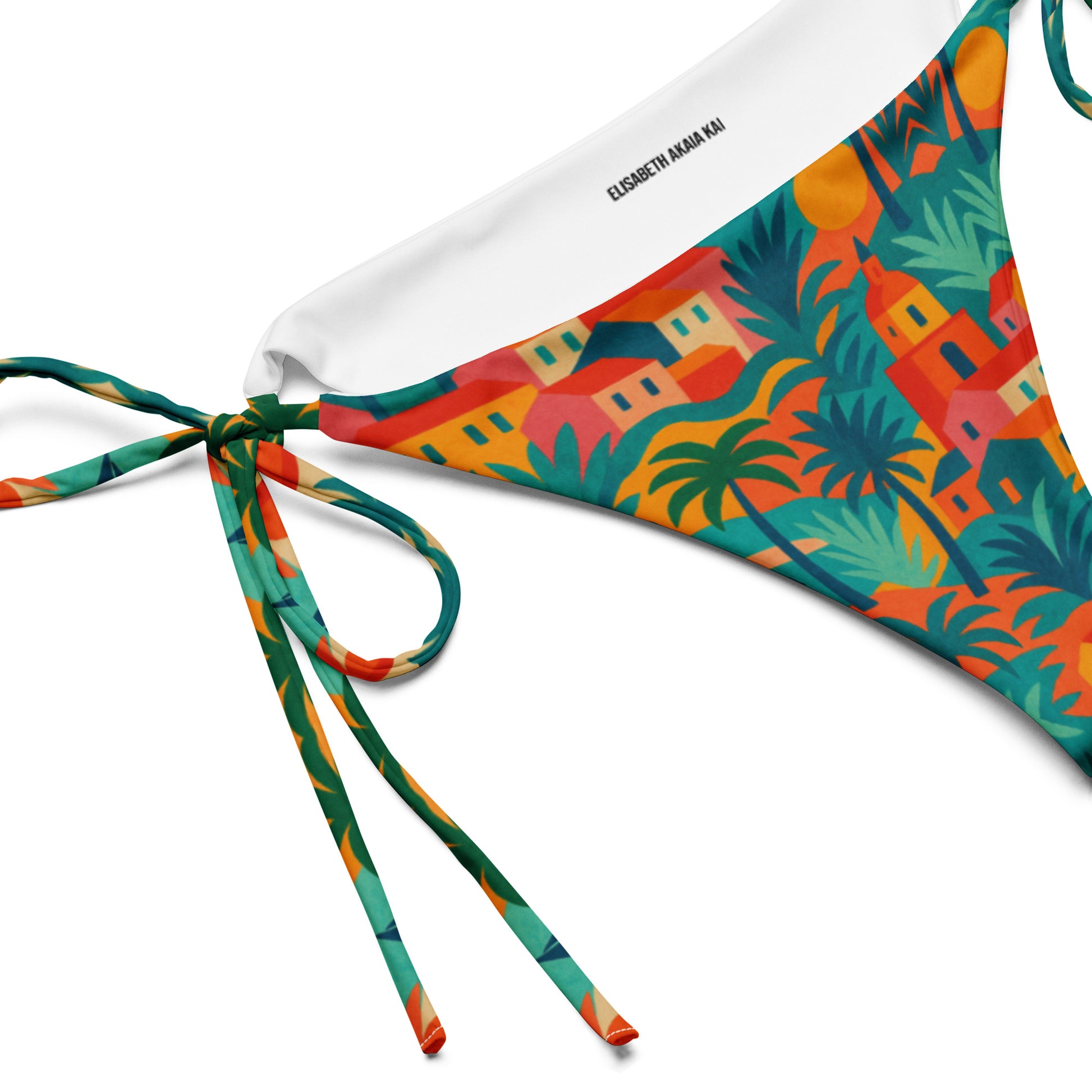 Bas de bikini triangle luxe Rêve Riviera detail en tissu recyclé, imprimé artistique inspiré de Saint-Tropez, présenté sur un lit de plage avec accessoires élégants.