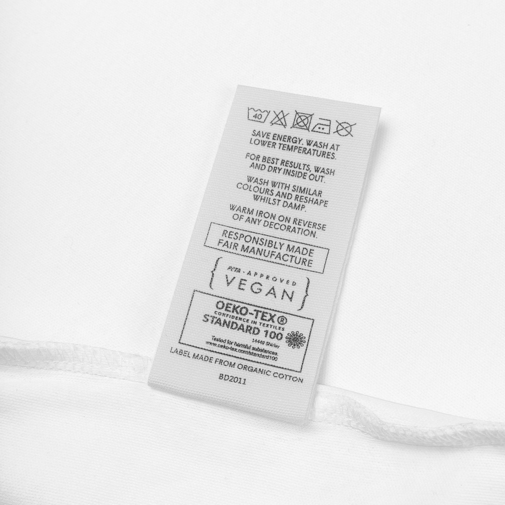 Étiquette du body bébé Mikaya en coton biologique, indiquant la fabrication responsable, la certification Oeko-Tex Standard 100 et la mention vegan.
