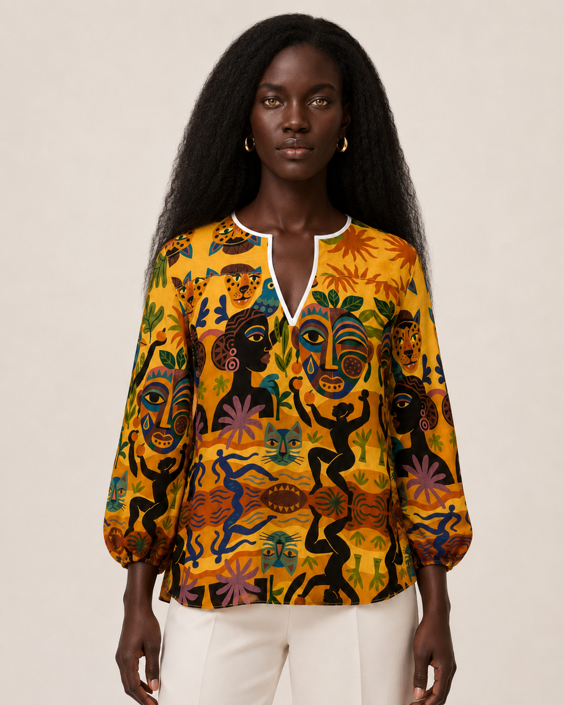Vue de face de la Blouse Tanéa portée avec un pantalon ivoire. Cette photographie présente sa coupe fluide, son encolure en V et son imprimé artistique aux couleurs solaires.