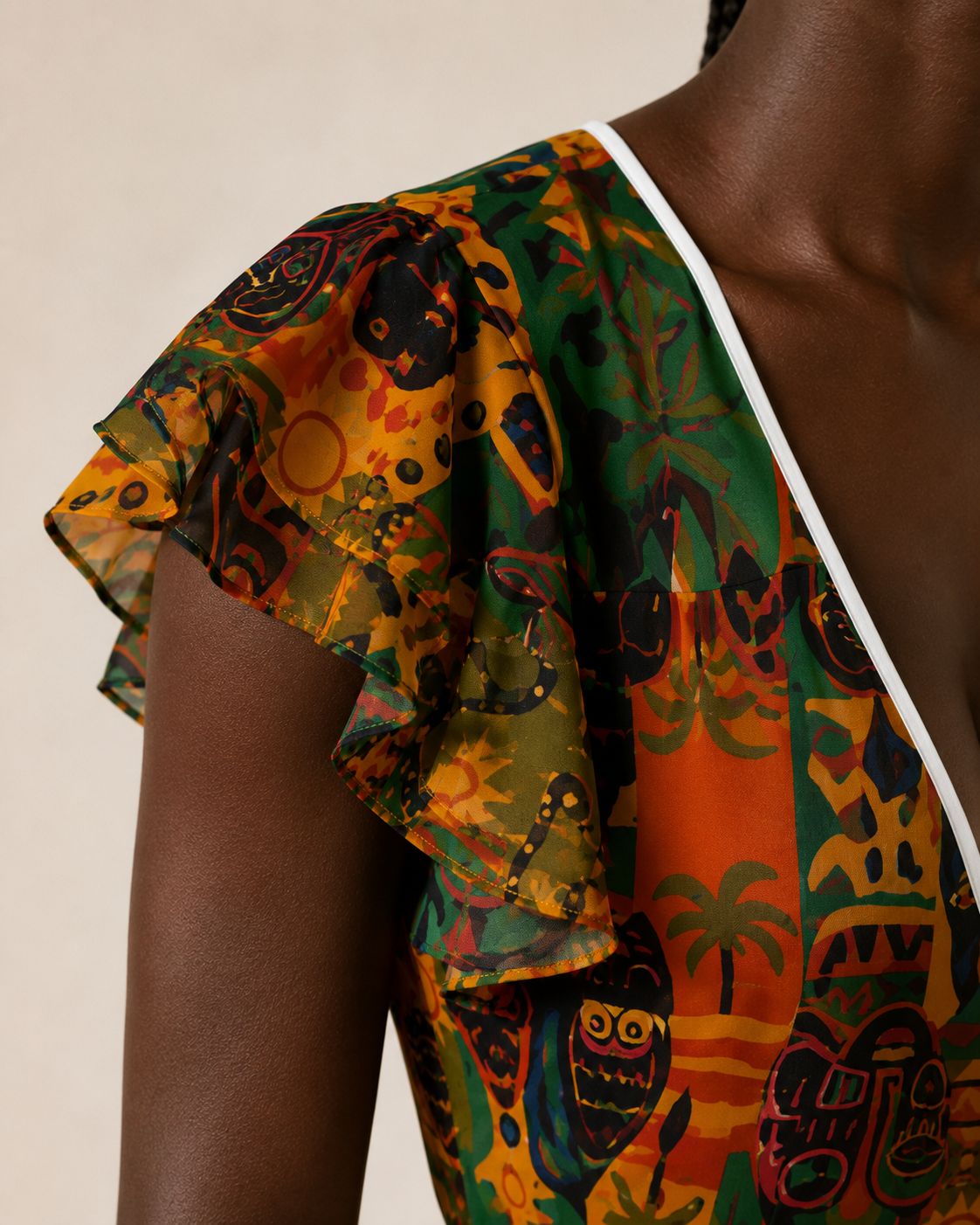 Détail de la manche volantée de la Robe Nzinga, mettant en valeur la légèreté du tissu, la précision des coutures et la richesse de l’imprimé artistique vert, orange, ocre et noir.