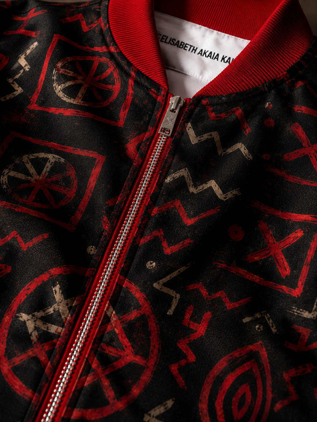 Zoom sur les détails couture de la veste Élisabeth Akaïa Kaï : col rouge texturé, finitions premium, fermeture zippée et textile imprimé haute qualité inspiré de l’art contemporain africain.