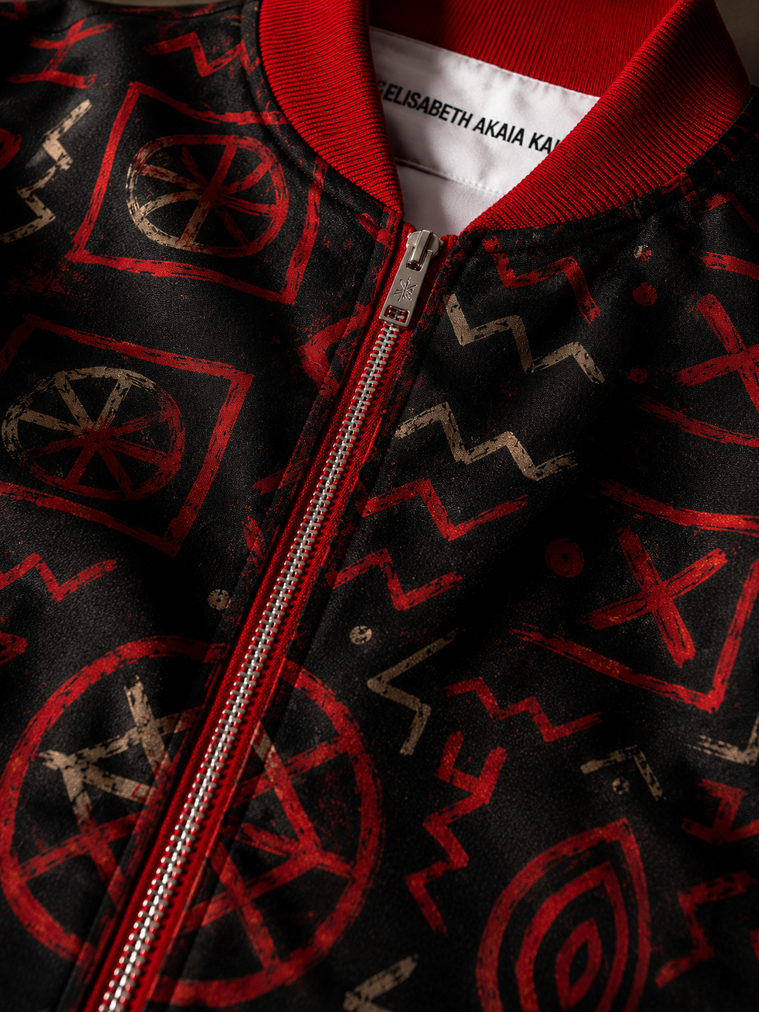 Zoom sur les détails couture de la veste Élisabeth Akaïa Kaï : col rouge texturé, finitions premium, fermeture zippée et textile imprimé haute qualité inspiré de l’art contemporain africain.