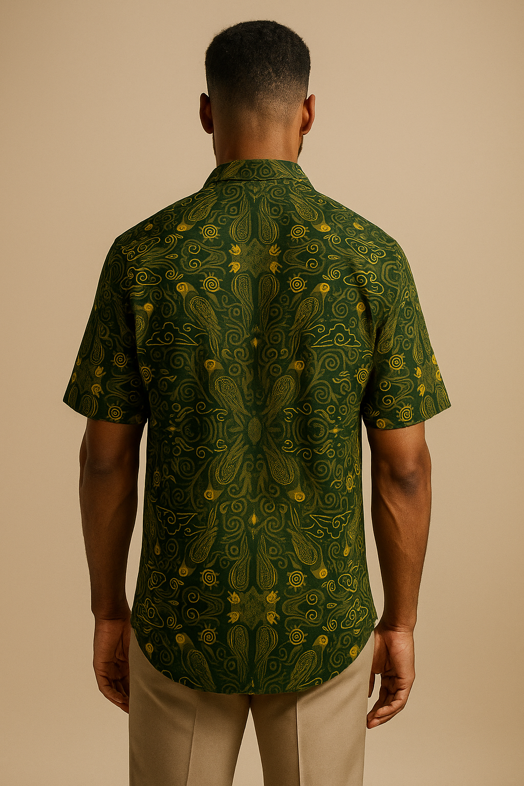 Vue arrière de la chemise M’bani mettant en valeur la symétrie parfaite de ses motifs dorés sur fond vert émeraude. Une pièce d’art vestimentaire signée Élisabeth Akaïa Kaï, alliant design gabonais et savoir-faire artisanal.