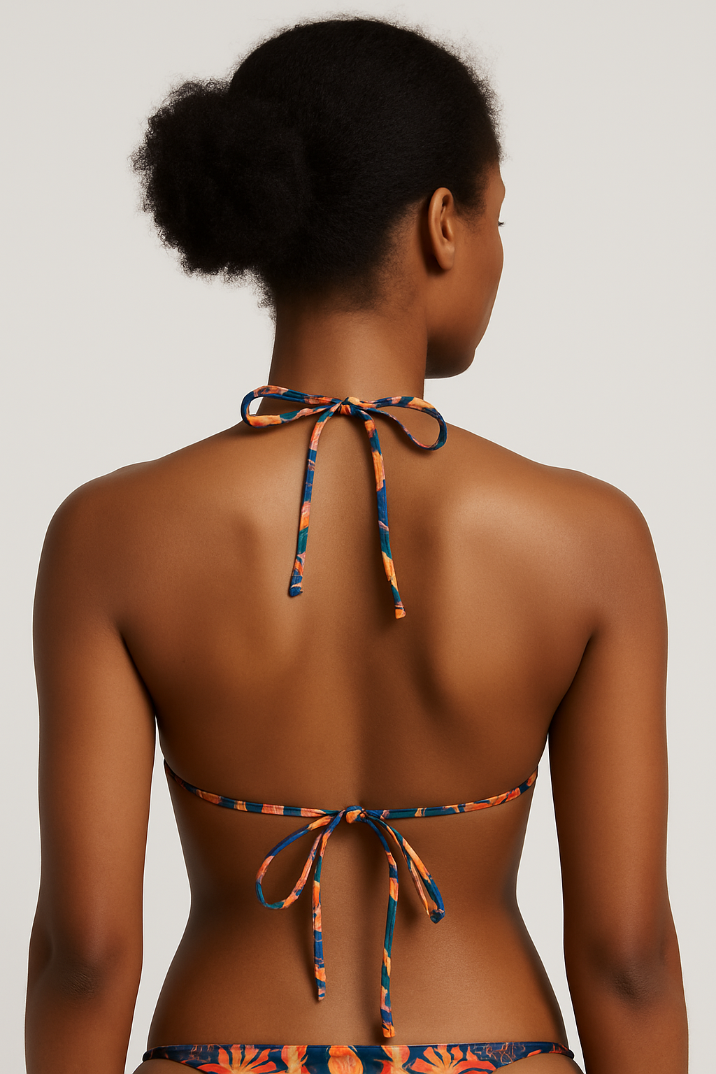 Vue arrière d’une femme noire portant le haut de bikini Isla Sol, détails des liens noués au dos, imprimé coloré et fond neutre – mode estivale éthique et inclusive