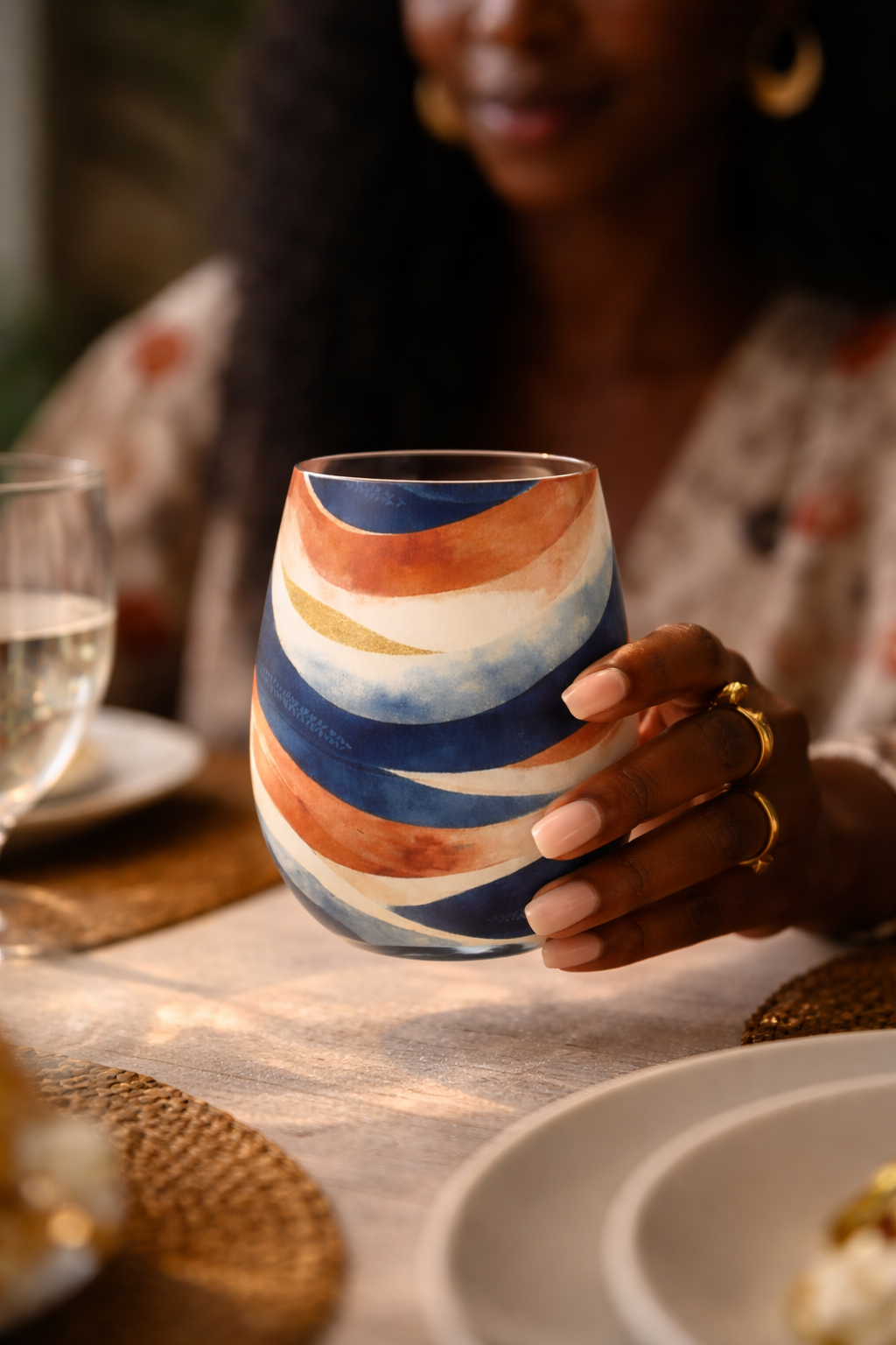 Verre décoratif de luxe MBEYA inspiré de la culture gabonaise, tenu à table par une femme noire, motifs artistiques peints à la main, pièce de décoration afro-luxe pour art de la table et intérieur haut de gamme.