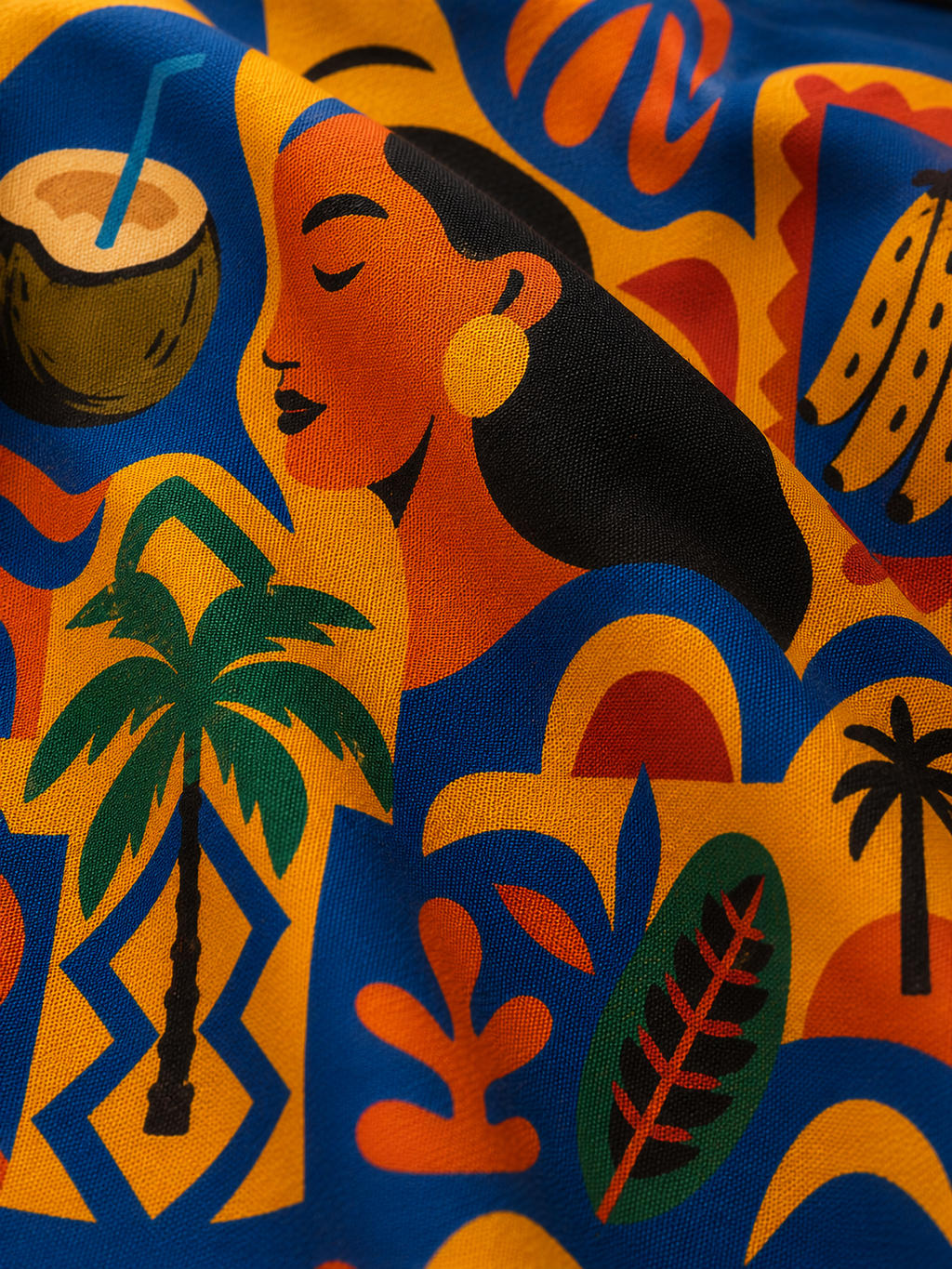 Admirez les illustrations emblématiques du pagne Isla Sol à travers un gros plan révélant les silhouettes féminines, les feuilles tropicales et les formes graphiques qui composent cette création originale.