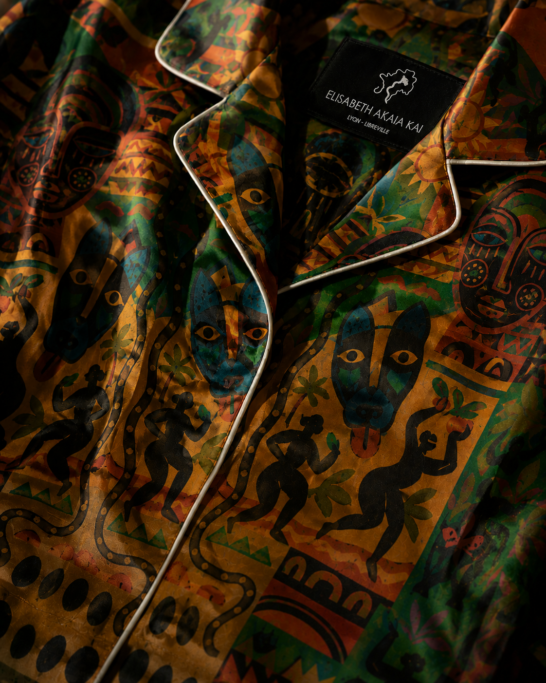 Chaque pli révèle la profondeur du textile.
La lumière glisse sur la soie et fait apparaître les symboles, les soleils et les formes inspirées des arts africains traditionnels réinterprétés dans une esthétique couture contemporaine.