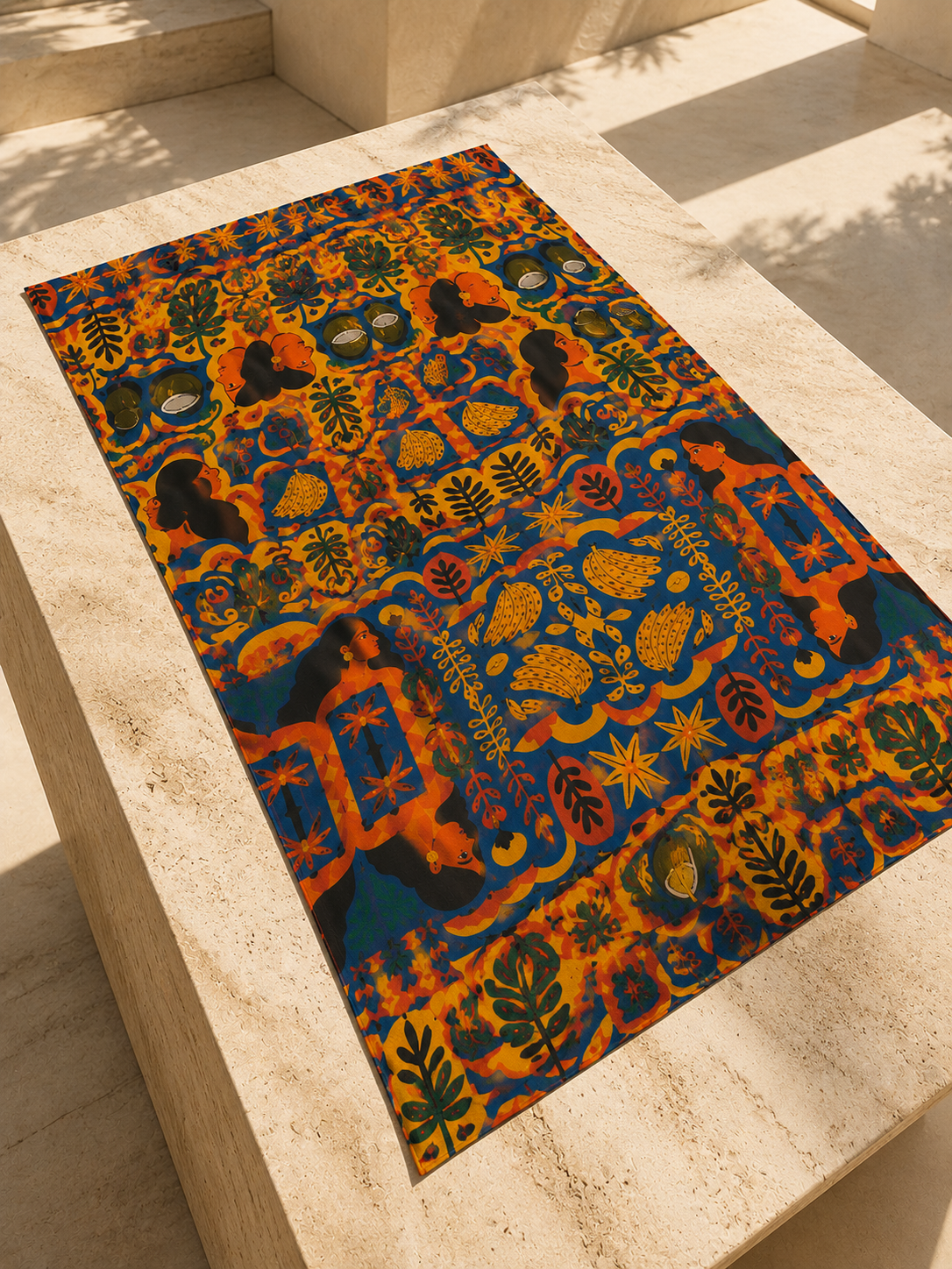 Photographie editoriale du pareo Isla Sol parfaitement deploie sur une table en travertin. Une mise en scene lumineuse qui sublime les couleurs et les details du motif.