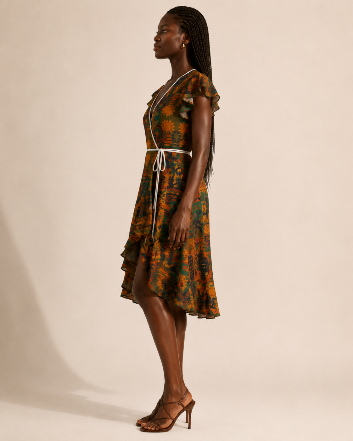 Vue de profil de la Robe à Volants Nzinga révélant la fluidité de sa jupe asymétrique, le volume de ses manches et sa taille délicatement marquée par une fine ceinture blanche.