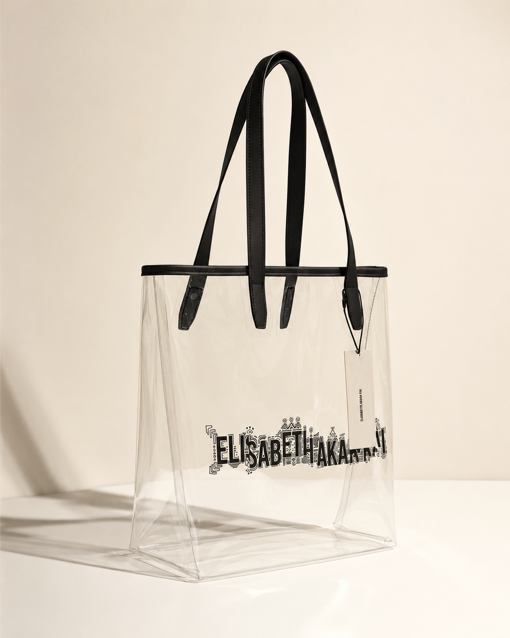 Le sac cabas transparent Elisabeth Akaia Kai est mis en lumiere dans une ambiance minimaliste inspiree des grandes maisons de luxe. Une creation contemporaine au design epure et intemporel.