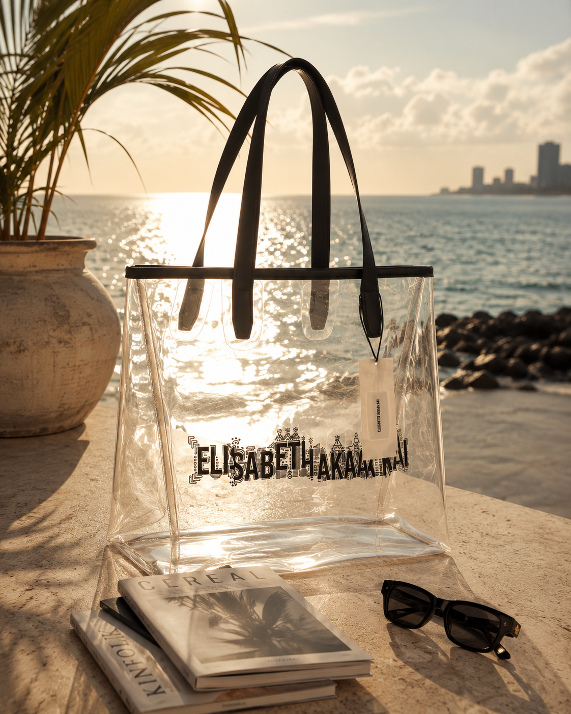 Le sac cabas transparent Elisabeth Akaia Kai illumine une scene face a l'ocean Atlantique. Une photographie lifestyle de luxe inspiree de Libreville, entre elegance contemporaine et evasion.