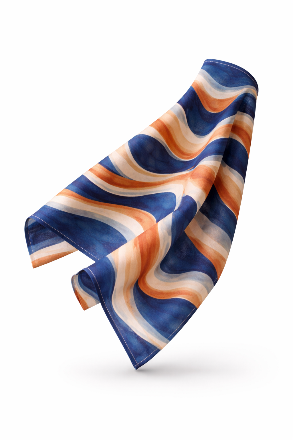 Photographie d’objet sur fond blanc d’une serviette de table Mbyela 40 × 40 cm en mouvement, dévoilant le motif ondulations solaires aux nuances de bleu profond, terracotta et sable, mettant en valeur la fluidité du textile et son design contemporain.