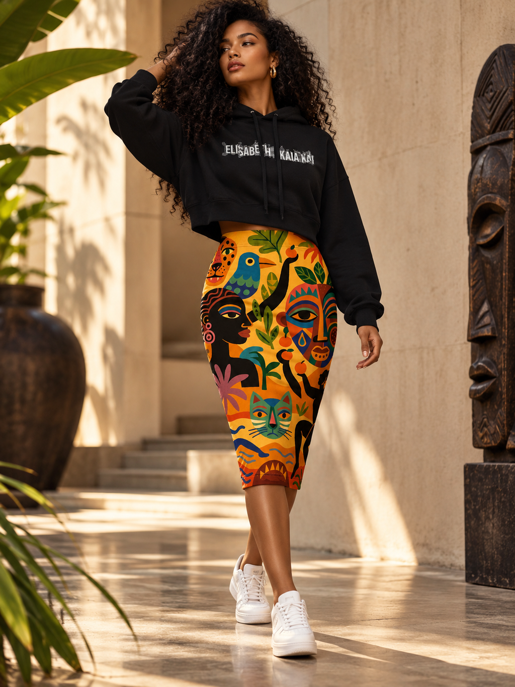 Éditorial de mode afro-luxe : mannequin en sweat court à capuche noir EAK et jupe crayon à imprimé pictural multicolore.