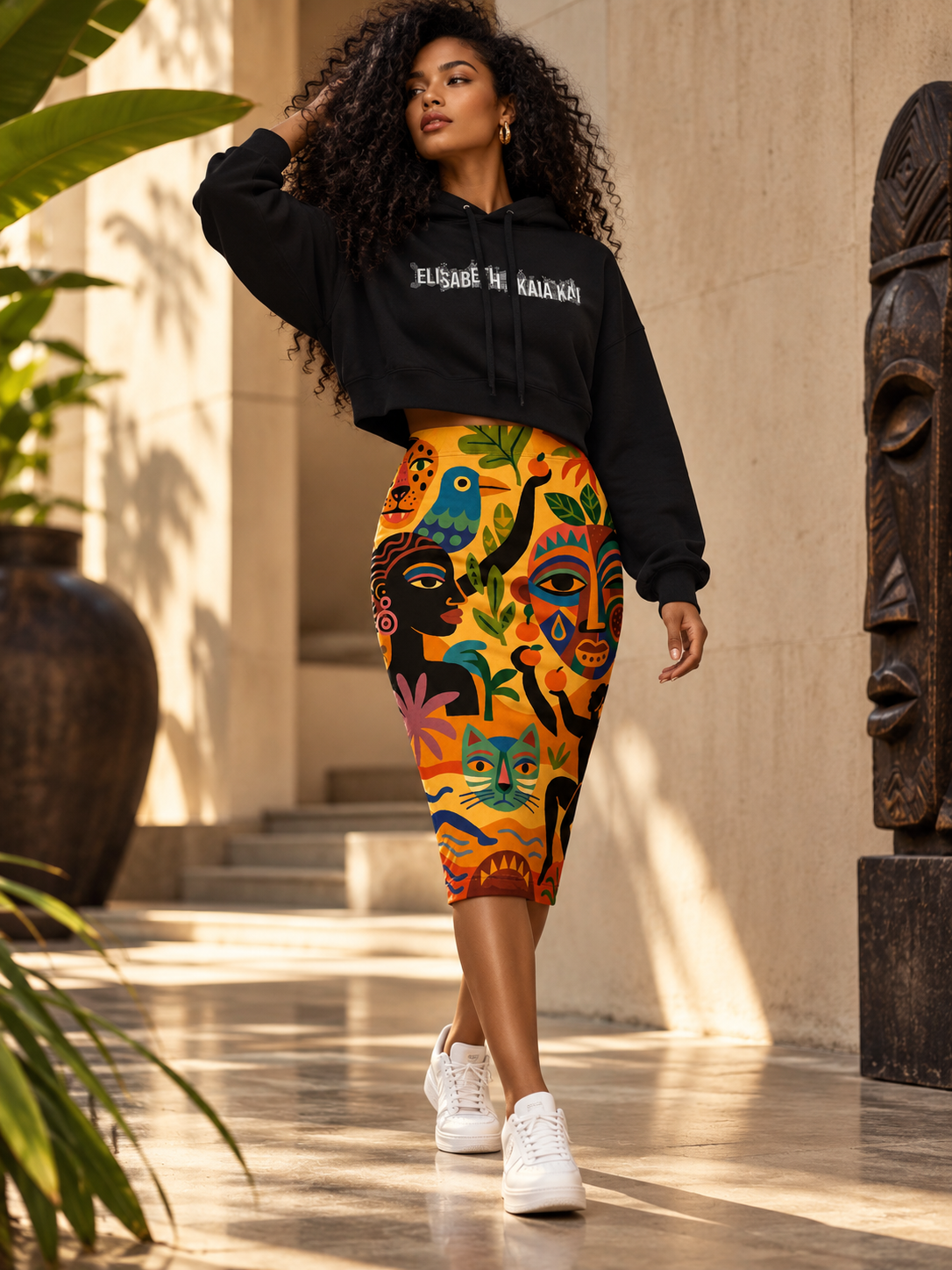 Éditorial de mode afro-luxe : mannequin en sweat court à capuche noir EAK et jupe crayon à imprimé pictural multicolore.