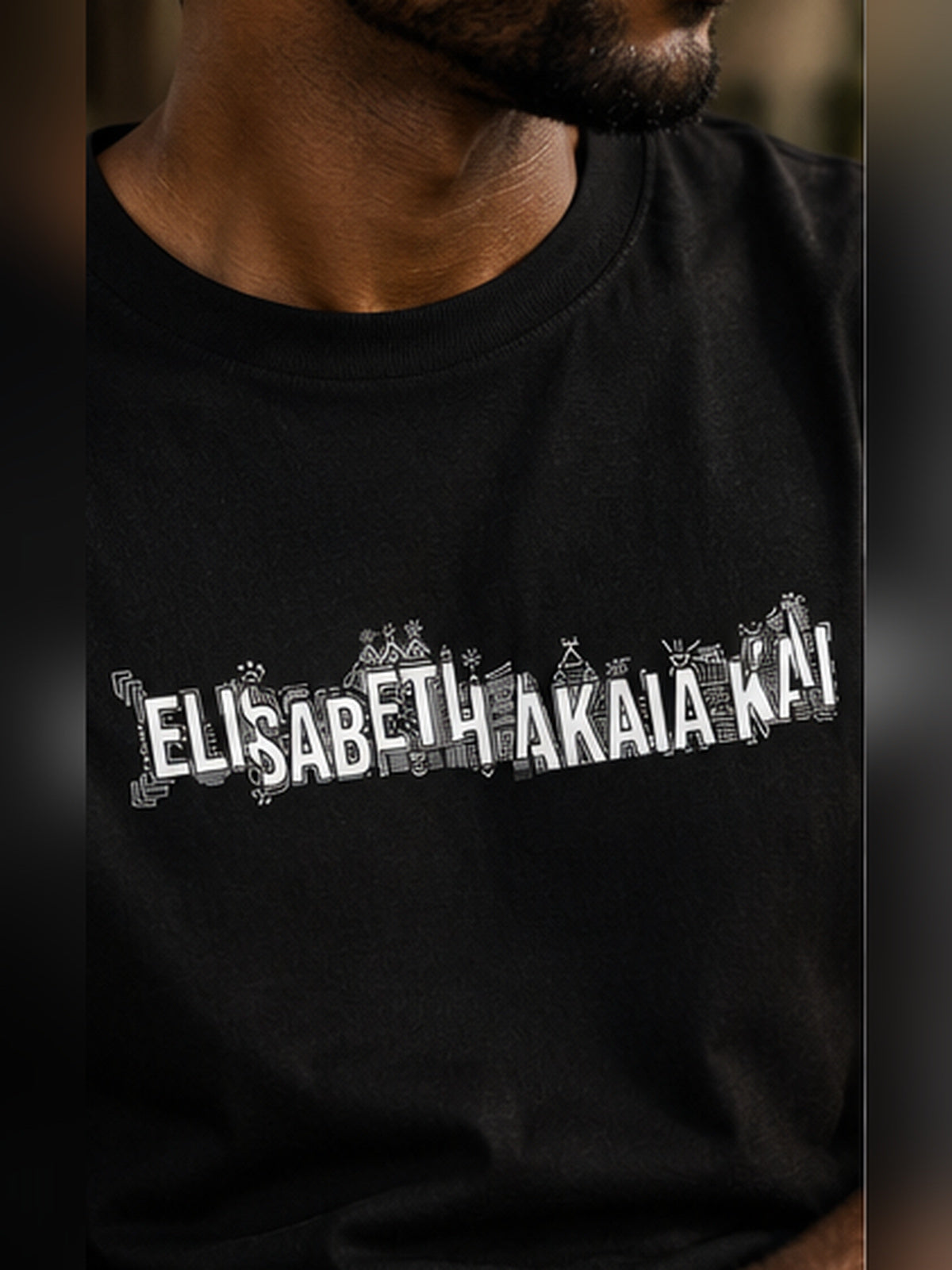 Gros plan du t-shirt KAÏ noir porté par un homme, montrant l'imprimé graphique blanc Élisabeth Akaïa Kaï sur la poitrine.
