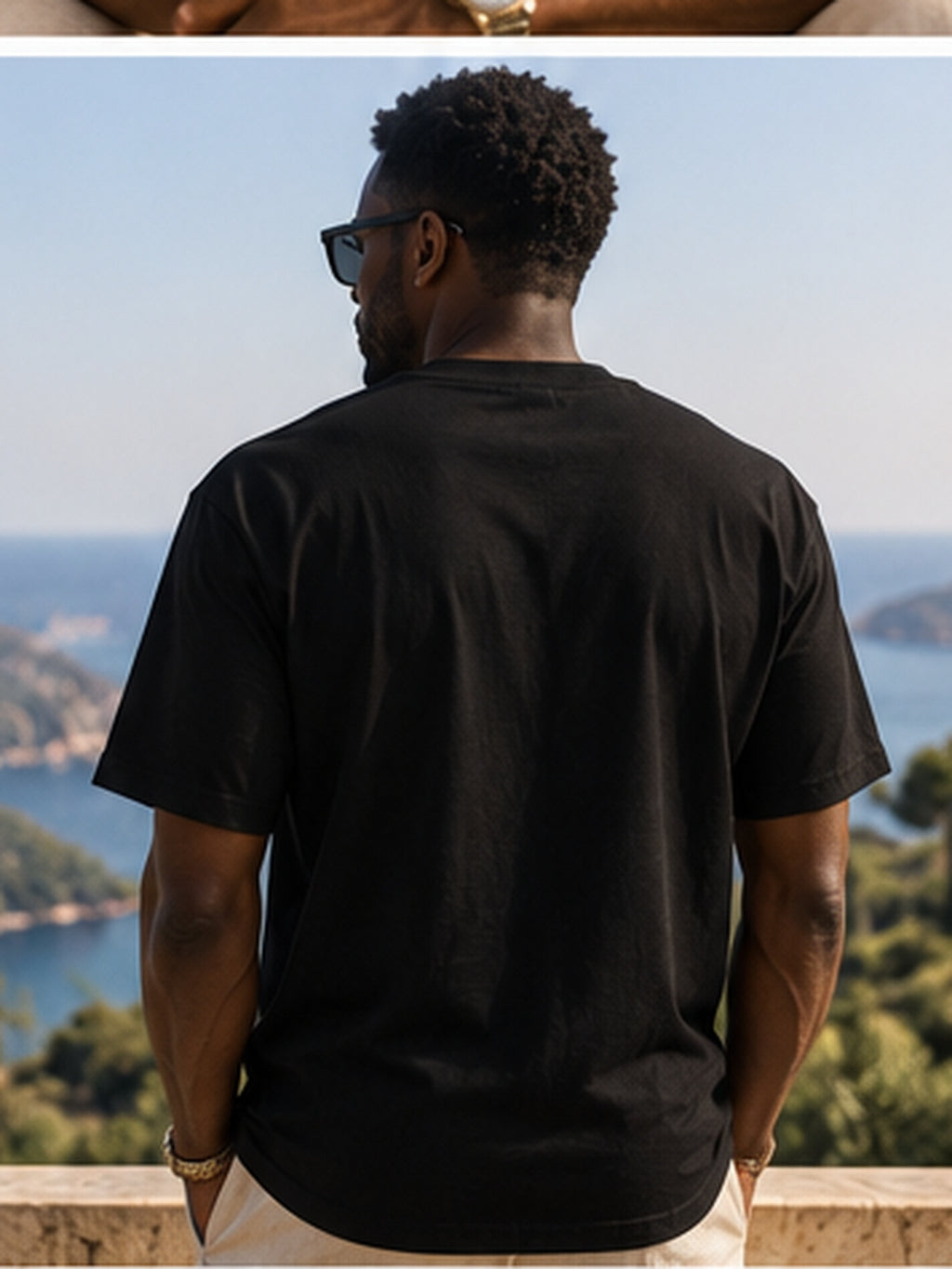 Vue de dos du t-shirt KAÏ noir à manches courtes porté par un homme sur une terrasse avec panorama côtier, dos uni sans imprimé.