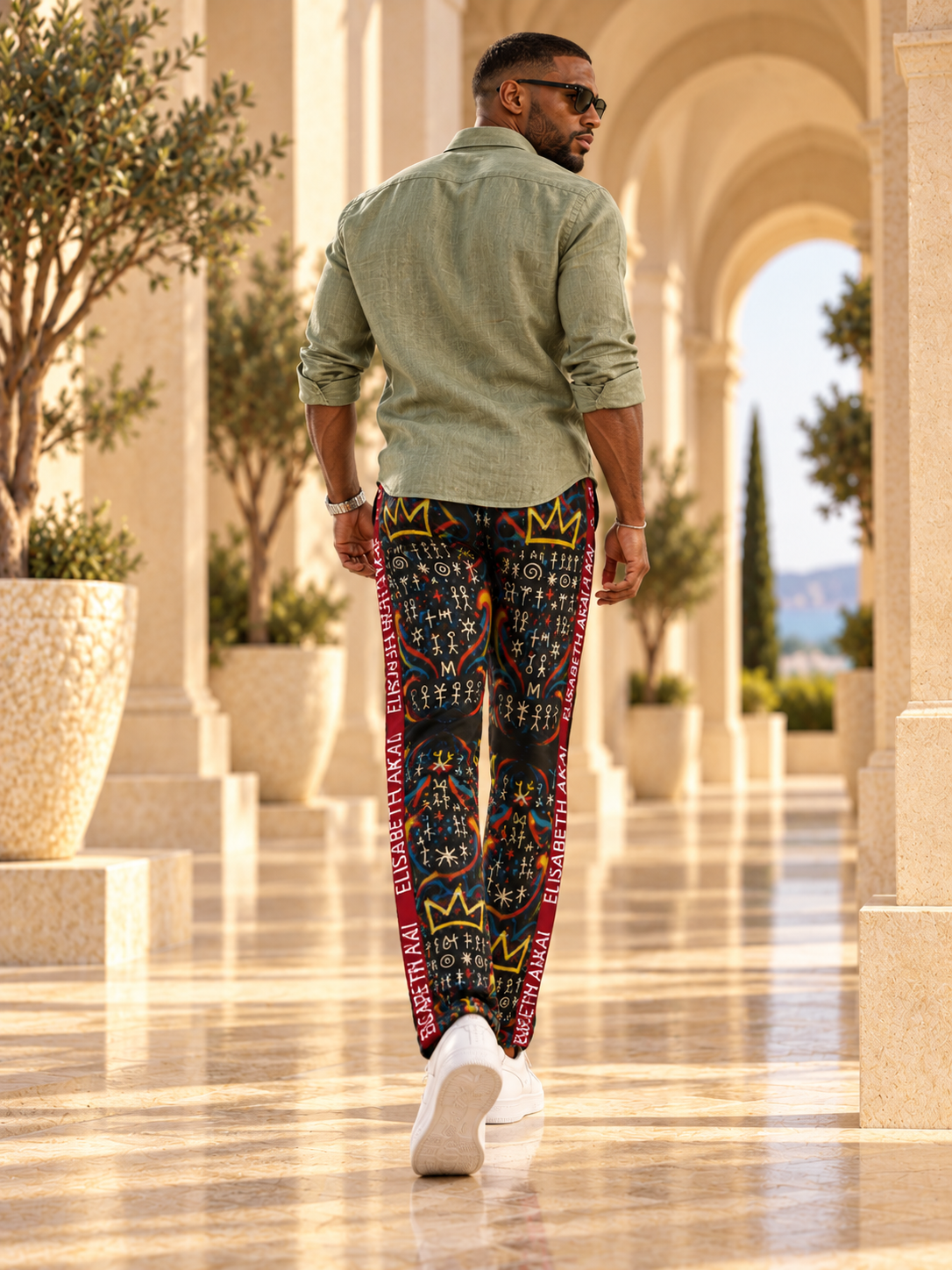 Vue de dos du pantalon MIENGO SEKIANI porté par un mannequin homme, imprimé multicolore sur fond noir et bandes bordeaux.